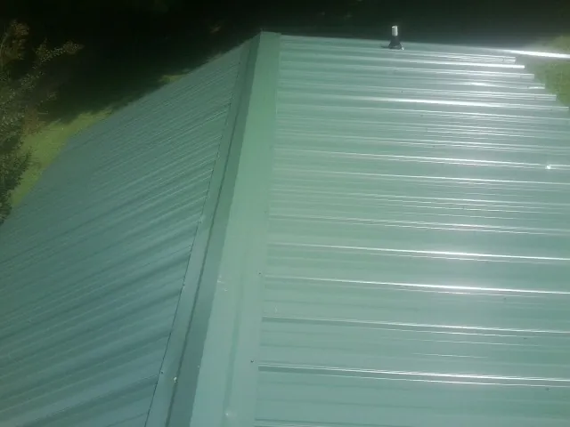 New green metal panels meeting at the ridge of a roof — Flat Roof Repair work by our crew in Washingtonville