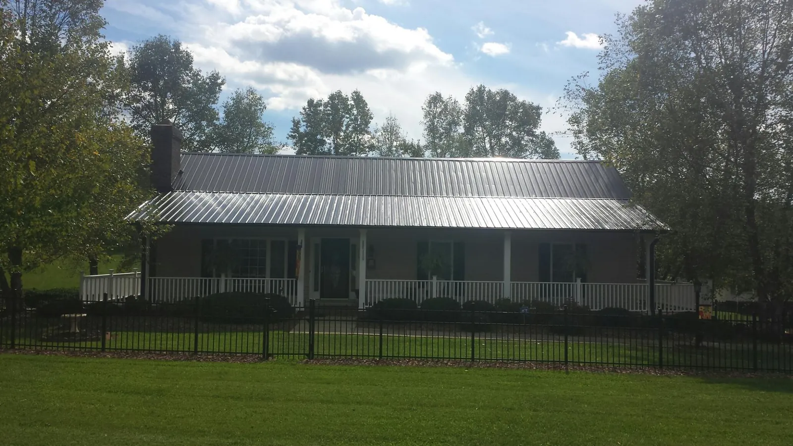 Gray metal roof on a brick ranch with a full width front porch — Gutter Guard Installation work by our crew in Washingtonville