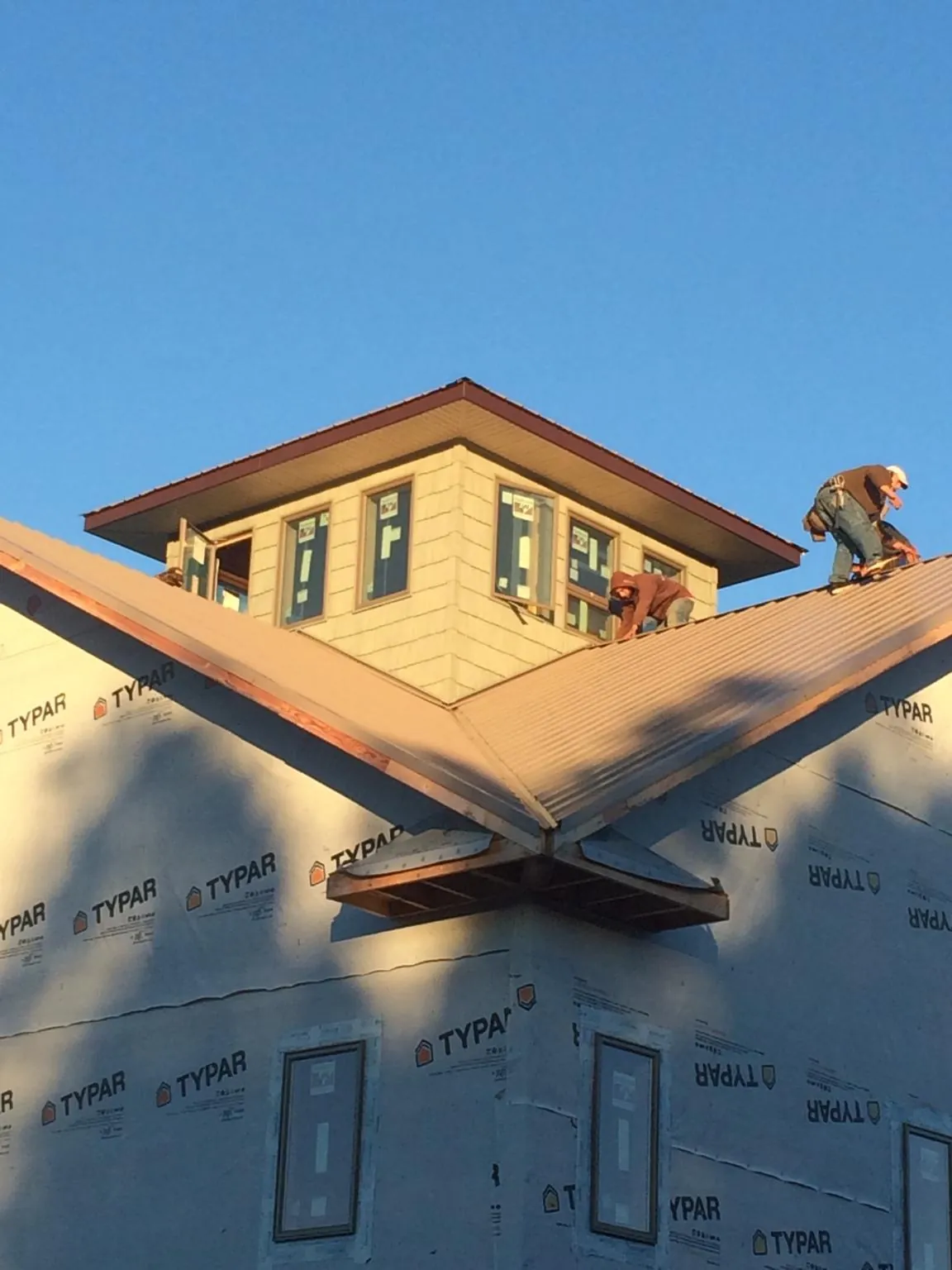Roofers working around a rooftop cupola on a new metal roof at sunset — Roof Waterproofing in Washingtonville by Roofing Brothers